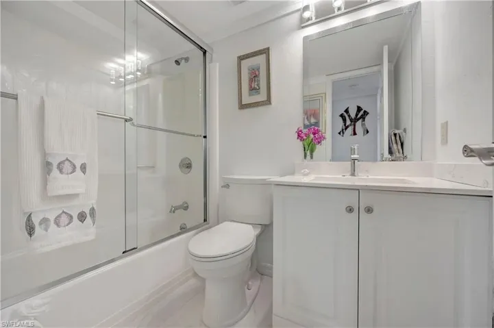 Full bathroom featuring crown molding, shower / bath combination with glass door, toilet, vanity, and tile patterned floors