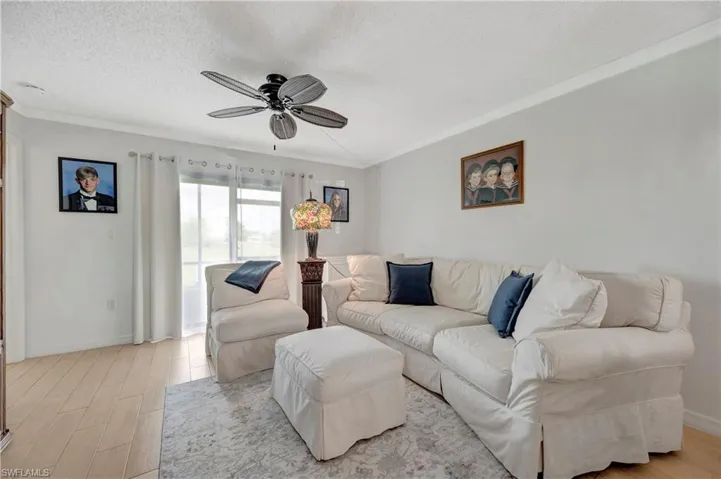 Living room featuring hardwood / wood-style floors, a textured ceiling, ornamental molding, and ceiling fan