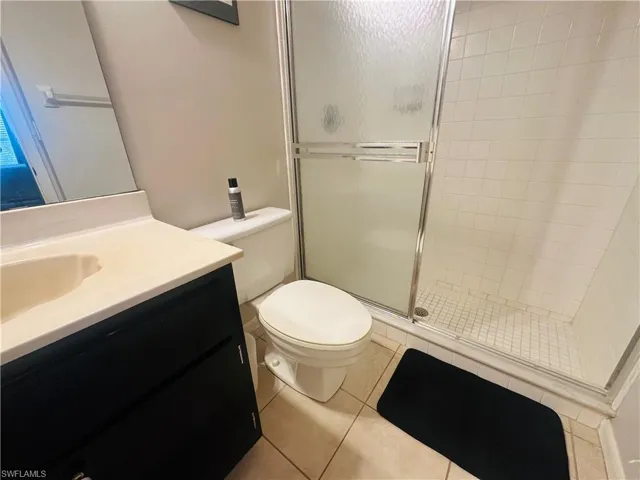 Bathroom featuring a stall shower, vanity, toilet, and tile patterned floors