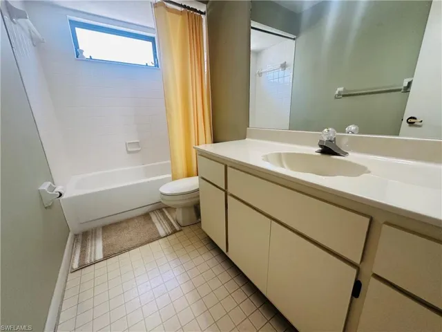 Bathroom featuring toilet, shower / bath combo with shower curtain, vanity, and tile patterned floors