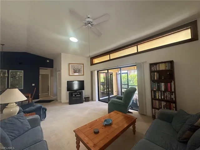 Living room featuring light colored carpet, a ceiling fan, and vaulted ceiling