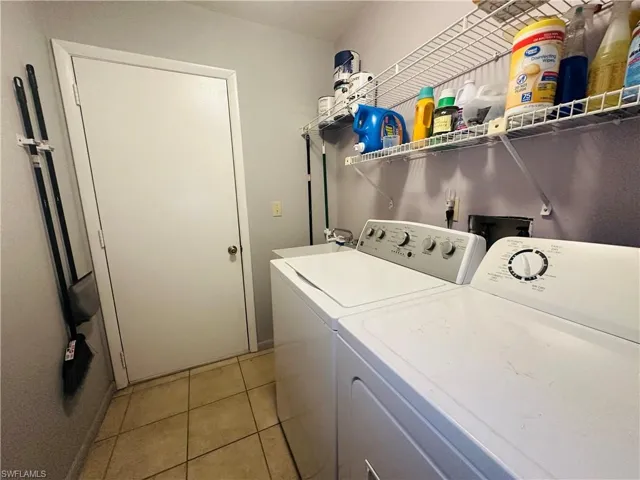 Laundry area with independent washer and dryer and light tile patterned floors
