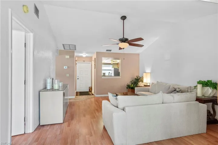 Living room featuring light wood-style flooring, ceiling fan, and vaulted ceiling