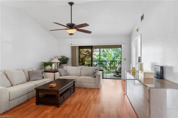 Living room featuring ceiling fan, high vaulted ceiling, and light wood-style floors