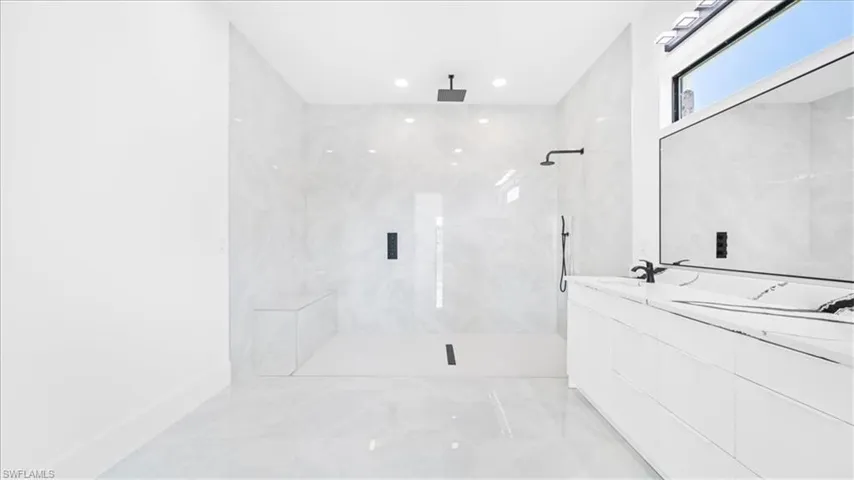 Full bathroom featuring double vanity, light marble finish floors, a marble finish shower, and recessed lighting