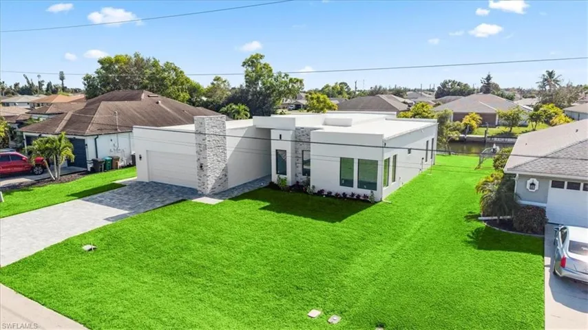 View of front facade with a front yard, a residential view, and decorative driveway