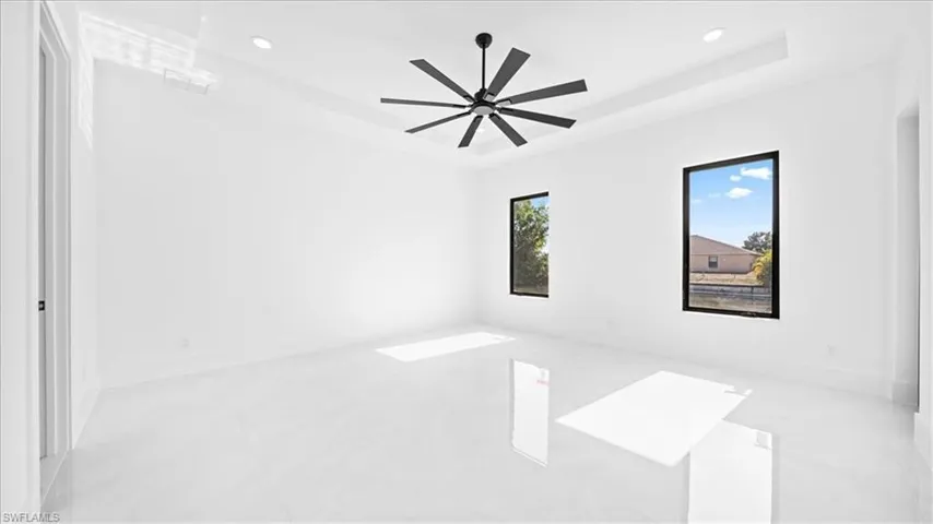 Unfurnished room featuring a tray ceiling, recessed lighting, and ceiling fan