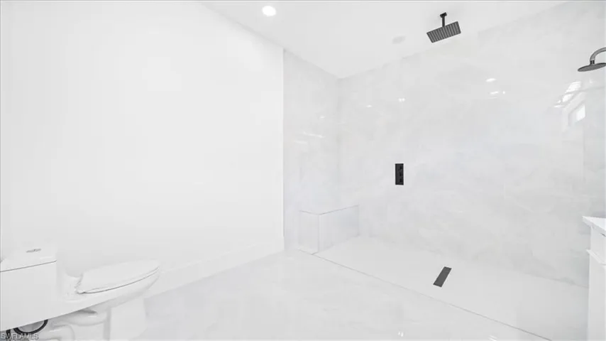 Full bath featuring a marble finish shower, marble look tile flooring, and recessed lighting
