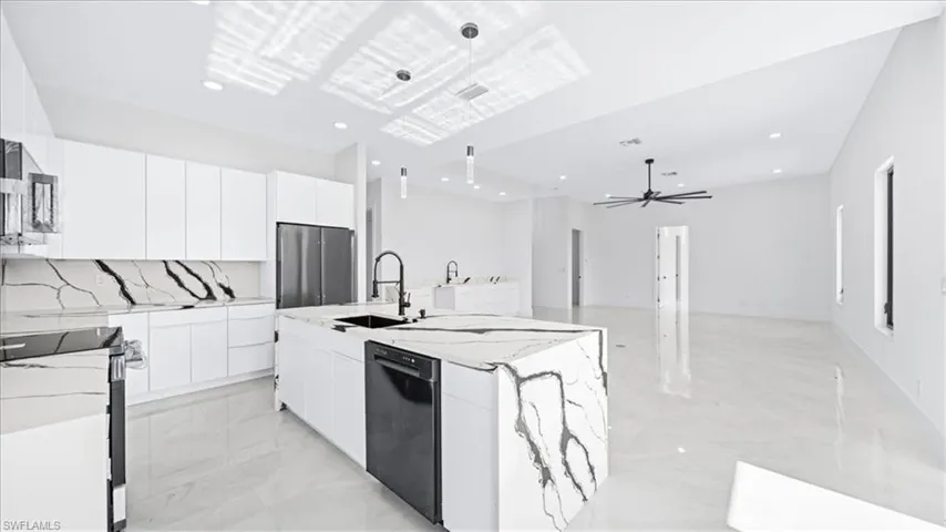 Kitchen with white cabinetry, modern cabinets, stainless steel appliances, a ceiling fan, and light stone counters