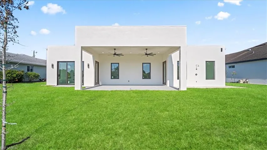 Back of property with a patio, stucco siding, ceiling fan, and a yard