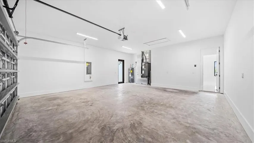 Garage featuring heating unit, water heater, and electric panel