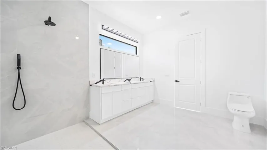 Bathroom featuring a marble finish shower and double vanity