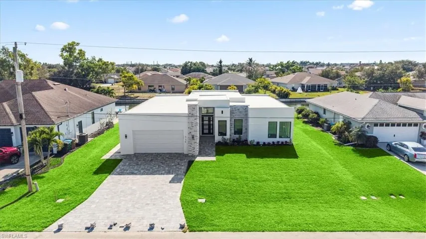 View of front facade featuring a residential view, decorative driveway, stucco siding, a front yard, and a garage
