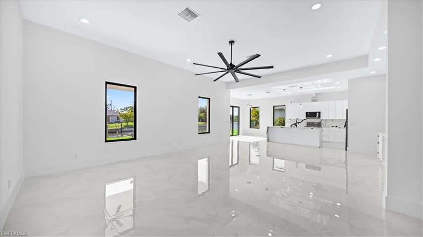 Unfurnished living room featuring plenty of natural light, recessed lighting, ceiling fan, and light marble finish flooring