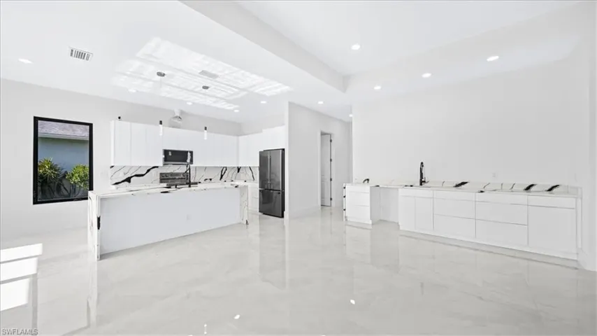 Kitchen with white cabinetry, open floor plan, a center island with sink, modern cabinets, and stainless steel appliances