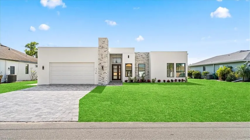 Contemporary house with decorative driveway, a front lawn, stucco siding, and an attached garage