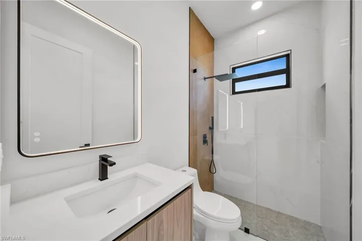 Bathroom featuring vanity, tiled shower, and toilet