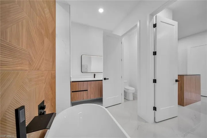 Bathroom featuring vanity, toilet, tile patterned flooring, and a tub