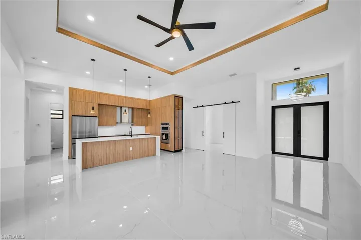Kitchen with decorative light fixtures, ceiling fan, light tile patterned floors, and an island with sink