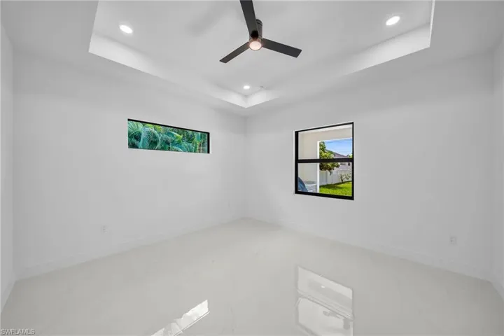 Unfurnished room with tile patterned flooring, ceiling fan, and a tray ceiling