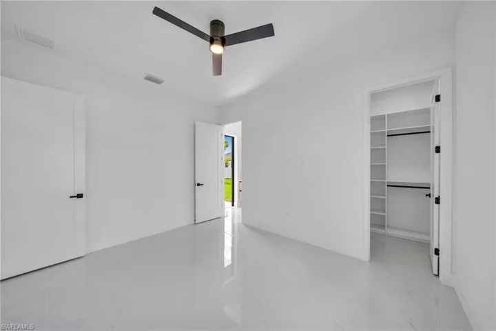 Unfurnished bedroom featuring light tile patterned flooring, a spacious closet, a closet, and ceiling fan