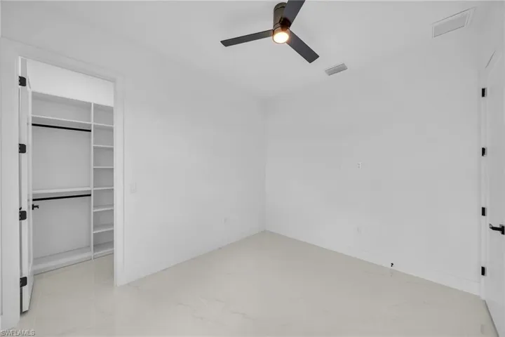 Unfurnished bedroom with light tile patterned flooring, a closet, and ceiling fan