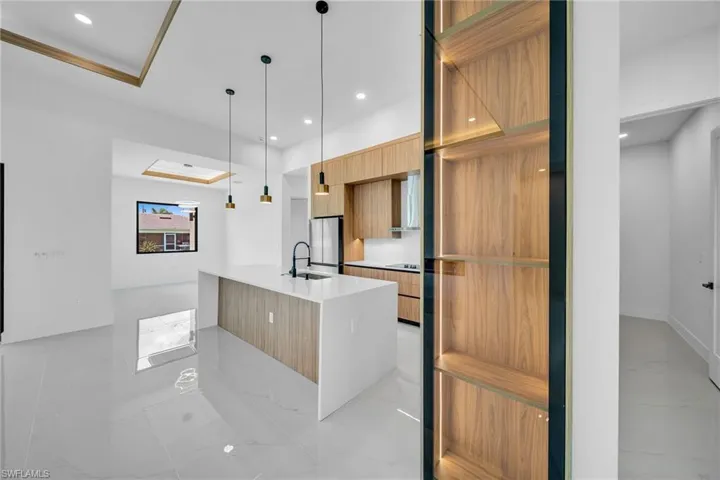 Kitchen with pendant lighting, stainless steel refrigerator, a center island with sink, and light tile patterned floors