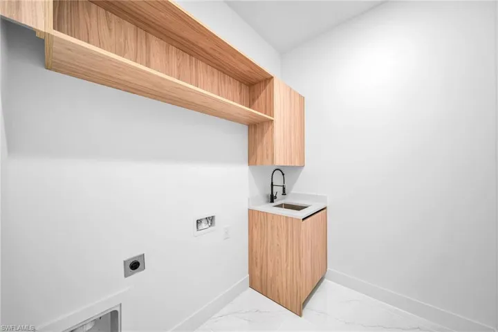 Laundry area with sink, hookup for a washing machine, light tile patterned floors, and hookup for an electric dryer