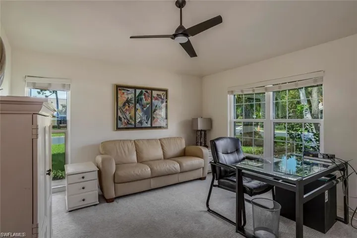 Living room featuring ceiling fan, carpet flooring, and a desk