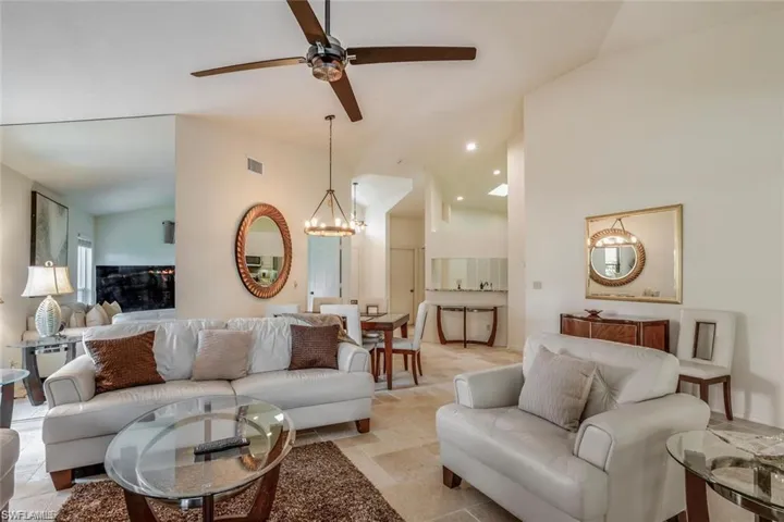 Living area featuring a ceiling fan, a chandelier, and high vaulted ceiling