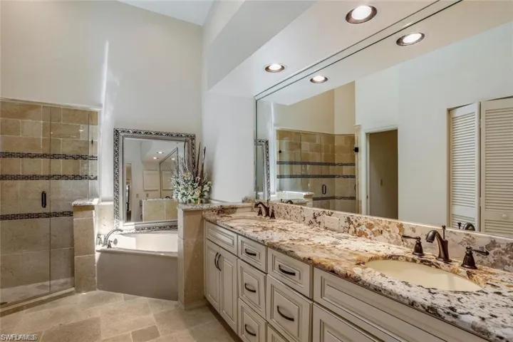 Bathroom featuring a bath, double vanity, a stall shower, recessed lighting, and a closet