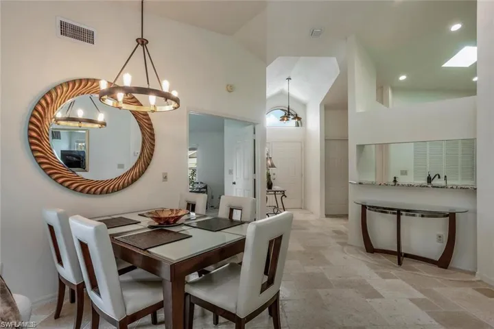 Dining area featuring high vaulted ceiling, a chandelier, and light stone finish floors