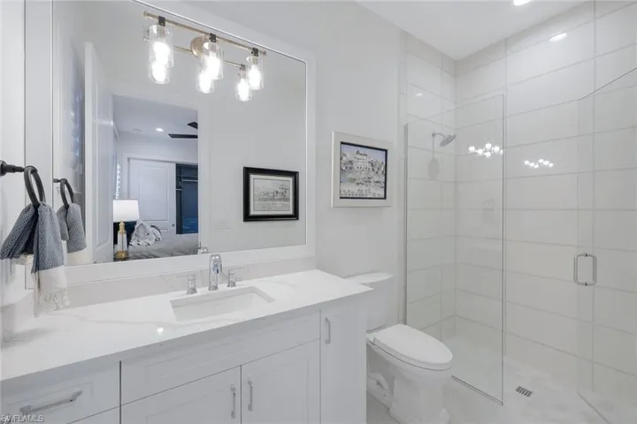 Bathroom featuring walk in shower, vanity, and toilet