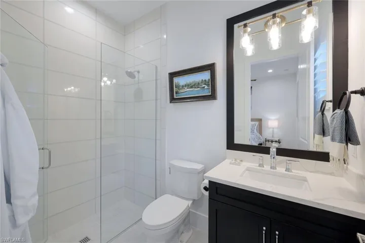 Bathroom with an enclosed shower, large vanity, and toilet
