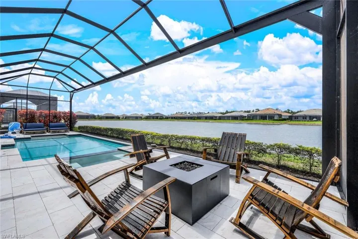 View of pool featuring a patio area, an outdoor fire pit, and a lanai