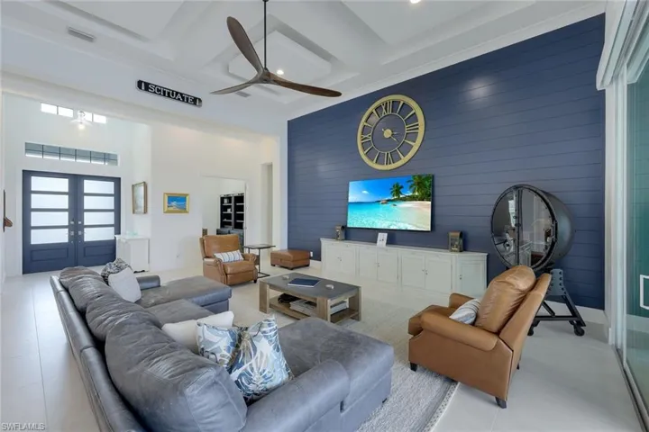 Tiled living room with coffered ceiling, beam ceiling, french doors, and ceiling fan