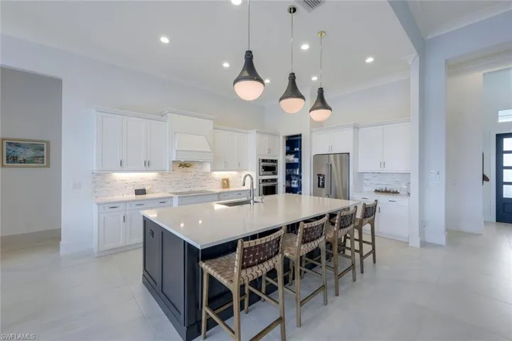 Kitchen with stainless steel appliances, sink, an island with sink, and backsplash