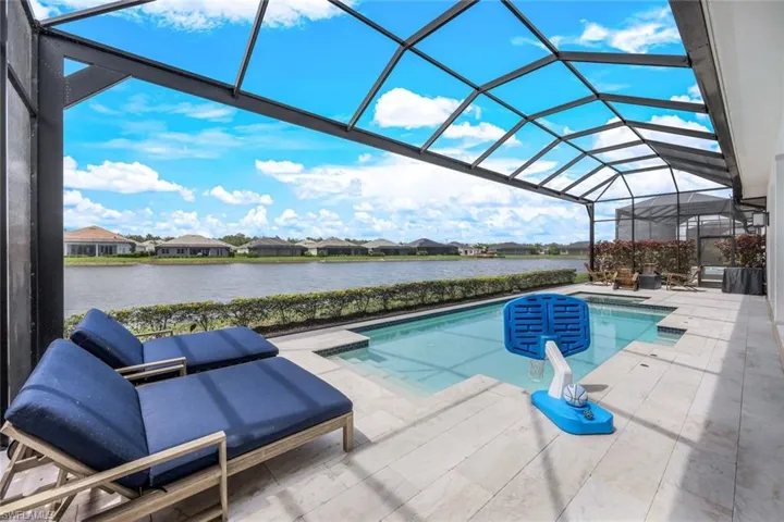 View of pool with a lanai, a patio area, and a water view
