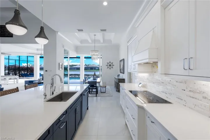 Kitchen featuring a tray ceiling, white cabinets, and pendant lighting