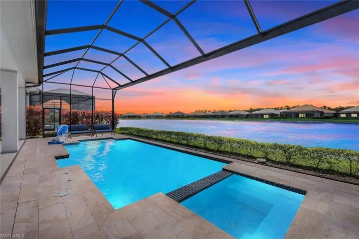 Pool at dusk featuring a lanai, an in ground hot tub, and a patio area