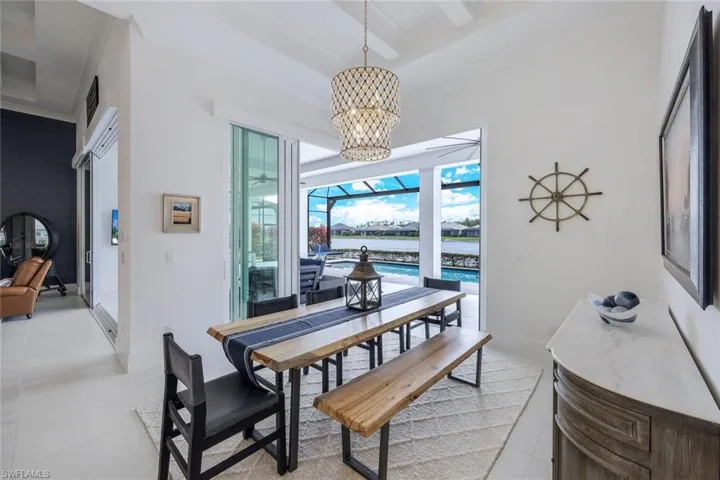 Dining area featuring beamed ceiling, light tile floors, a water view, and a chandelier