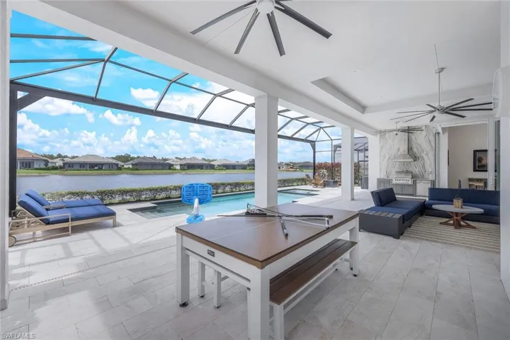 Sunroom / solarium featuring a water view, ceiling fan, and a tray ceiling