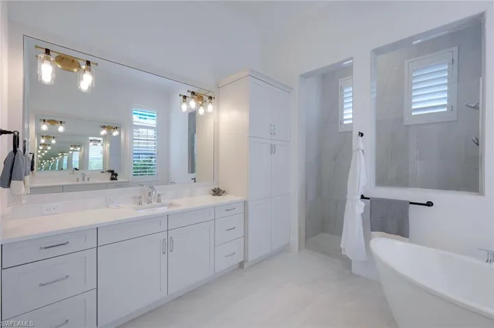 Bathroom with tile flooring, separate shower and tub, a wealth of natural light, and vanity