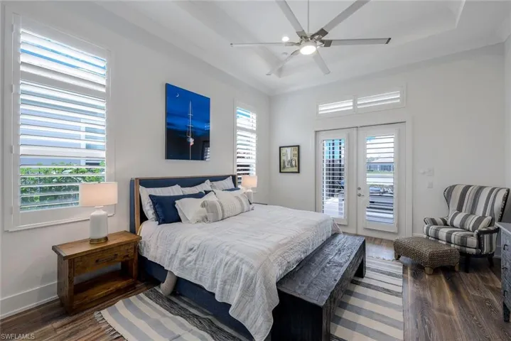 Bedroom featuring dark wood-type flooring, ceiling fan, access to outside, and multiple windows