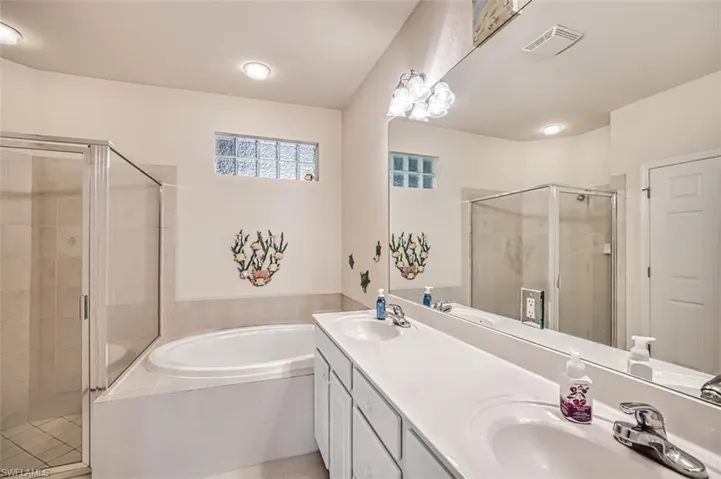 Bathroom with tile patterned floors, vanity, and separate shower and tub