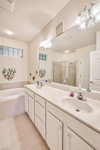 Bathroom featuring shower with separate bathtub, tile patterned floors, and vanity