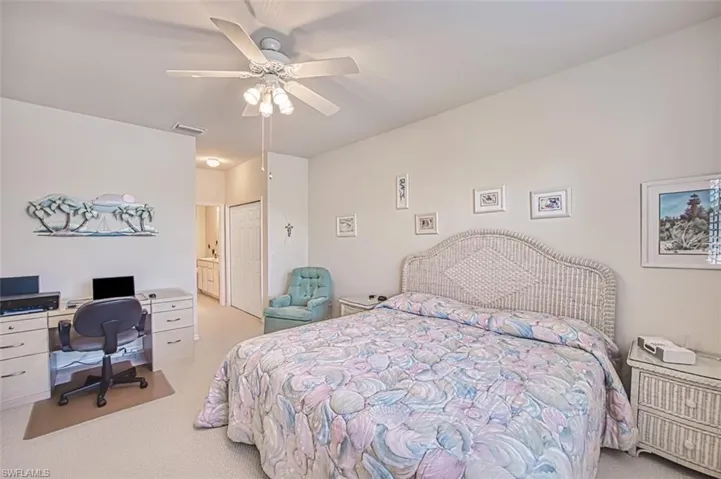 Carpeted bedroom featuring connected bathroom, ceiling fan, and a closet