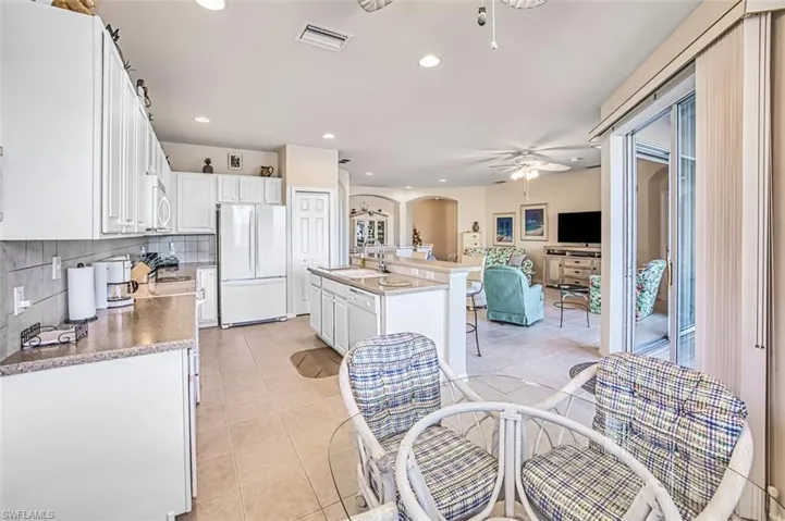 Kitchen featuring an island with sink, sink, white cabinets, and white appliances