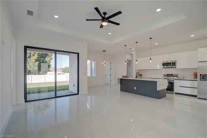 Kitchen with white cabinetry, open floor plan, modern cabinets, stainless steel appliances, and pendant lighting