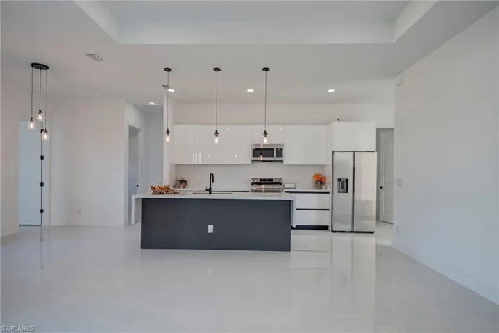 Kitchen featuring white cabinetry, appliances with stainless steel finishes, hanging light fixtures, a kitchen island with sink, and recessed lighting